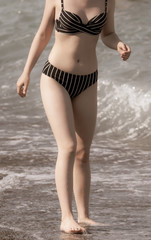 Fototapeta na wymiar Girl in a swimsuit on the beach in the summer.