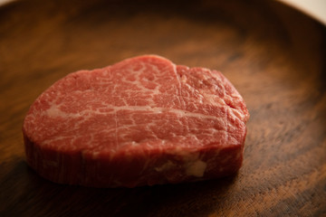 Raw Fillet Mignon Steak on the wooden round plate