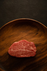 Raw Fillet Mignon Steak on the wooden round plate