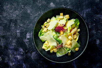 Classic Caesar salad with croutons, parmesan and white sauce in a ceramic bowl.. Close up. Top view