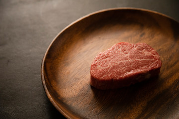 Raw Fillet Mignon Steak on the wooden round plate