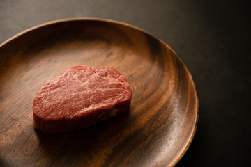 Raw Fillet Mignon Steak on the wooden round plate