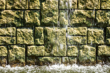 Water flows along a brick wall.