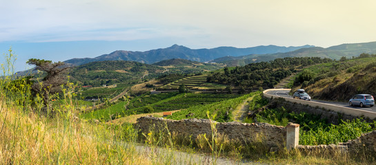 Travelling by car along the coastline of Mediterranean at summer on winding road over vineyards, mountain hills and the resort towns of the French Catalonia and Spain, sunset landscape.