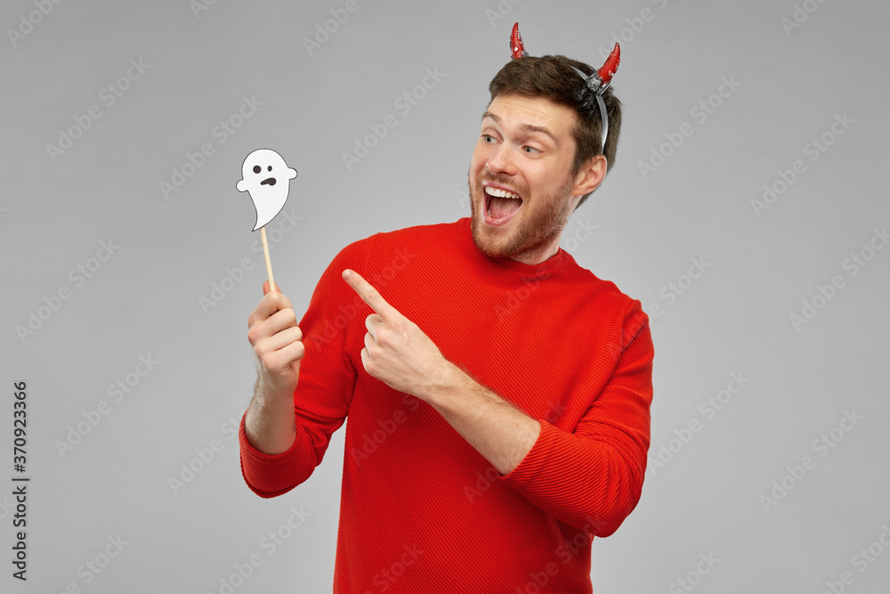 Wall mural holiday, photo booth and people concept - happy smiling man in halloween costume of devil with party accessory over grey background