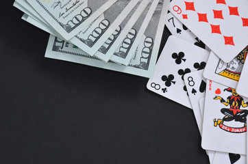 Dollars and cards on a black table.