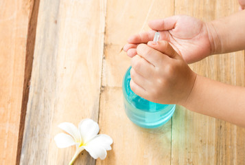 hand of children boy cleaning with hand clean alcohol gel for health care handle on background  wooden