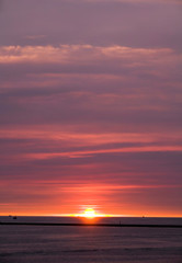 Brilliant orange-red clouds reflected into the ocean in a beautiful sunset
