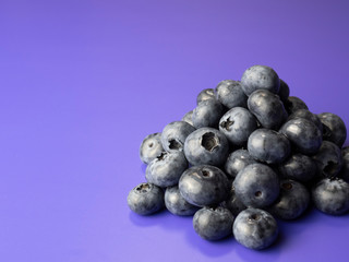 Pile of blueberries on purple background.