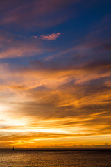 Brilliant orange-red clouds reflected into the ocean in a beautiful sunset