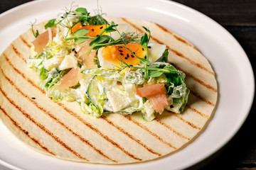 Close-up pita with fresh vegetable salad, smoked chicken, egg, herbs and black sesame seeds. Restaurant salad recipe