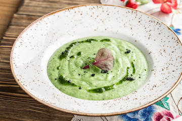 summer healthy green spinach soup on white plate on wooden table