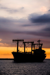 Sunset into the sea with the large ship silhouette.