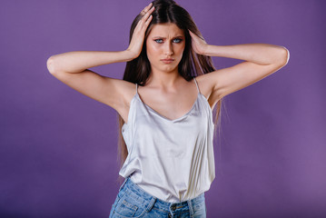 A young beautiful girl shows emotions and smiles in the Studio on a purple background. Girls for advertising