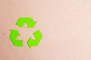 Green arrows recycle eco symbol on brown paper background. Recycled cycle sign.