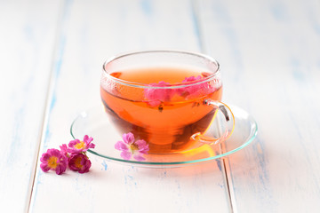 Flowers tea in a glass cup on the white table.