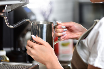 Young girl barista makes coffee on a large professional coffee machine, hands closeup. The concept of a small business and work for a student.