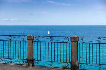 Widok z tarasu w Tropea na samotny jacht na morzu - obrazy, fototapety, plakaty
