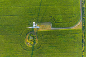Aerial photo above rotating propeller blade and housing  of wind turbine located on agriculture...