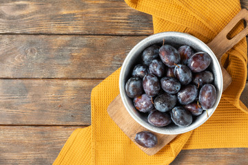 Ripe plum. Lots of plums in a metal bowl on a brown wooden table. Blue plums in a bowl. Top view with a space for text. Healthy fruits - Powered by Adobe