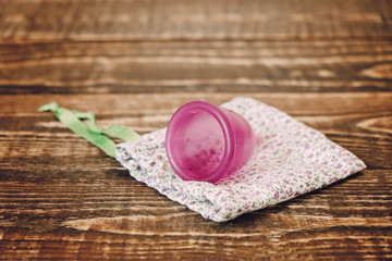 Menstrual cup and cotton bag on wooden background, concept of women's health and ecology of the planet
