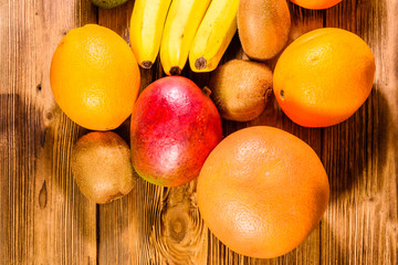 Still life with exotic fruits. Bananas, mango, oranges, avocado, grapefruit and kiwi fruits on wooden table. Top view