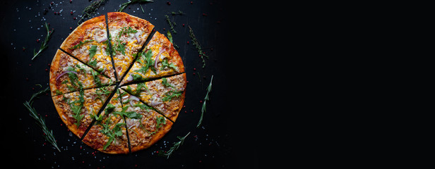 Tasty fresh baked pizza with tomatoes and basil on black background. Top view of hot delicious pizza. With copy space for text. Flat lay. Banner