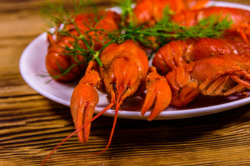 Plate with boiled crayfishes on wooden table