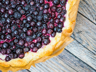 Macro view of open homemade pie with summer berries on a wooden table. Top view. Tart with berries. Freshly baked blackcurrant pie. Gourmet pastries, traditional European cuisine.