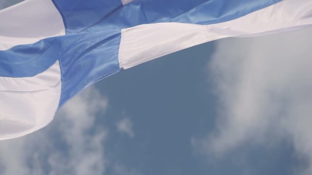 Slow-motion shot of a Finnish flag waving in the wind on a sunny day.