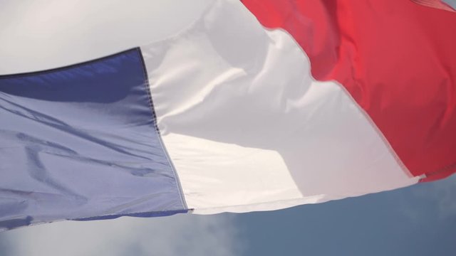 Slow-motion shot of a French flag waving in the wind on a sunny day.