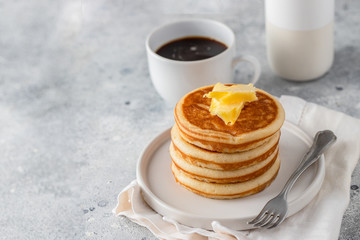 Stack of pancakes with butter , coffee cup and milk on light concrete background for classic American breakfast