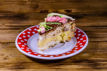 Plate with slice of Kiev cake with cream, nuts and meringue on a wooden table