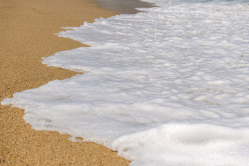 biała morska piana na gorącym żółtym piasku morskim