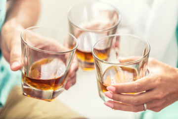 Group of friends toasting with glasses of whiskey brandy or rum indoors - closeup - obrazy, fototapety, plakaty
