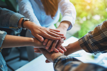 Closeup image of business team standing and joining their hands together in office