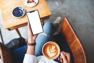 Top view mockup image of a woman holding mobile phone with blank white desktop screen while...