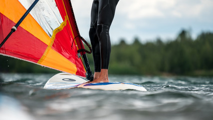Man in a wetsuit standing on a windsurfing board