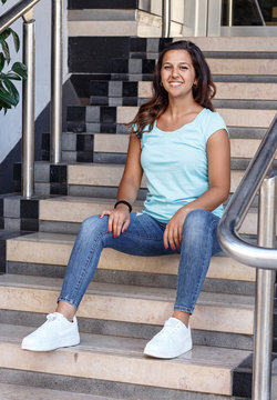 Young women wearing t-shirt and jeans sits on the steps