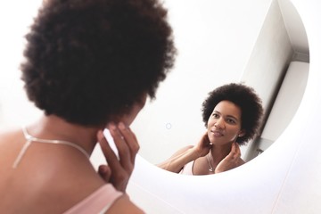 Beautiful woman looking in mirror at home