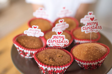 little girl eating cake. young woman cooking in kitchen. chocolate chip muffins. christmas cupcake with icing
