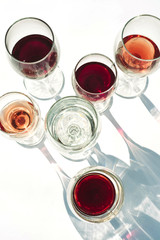 Glasses with red, white and rose wine on a white background.