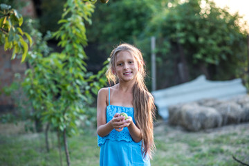 A beautiful long-haired girl picks pears in the garden. The child is holding a pear. The girl smiles and picks pears. Harvesting
