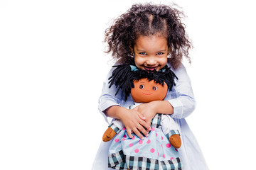 Portrait of a cute little african american girl hugging doll, isolated on white background