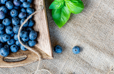 fresh blueberries  on a wooden rustic plate directly above on jute background
