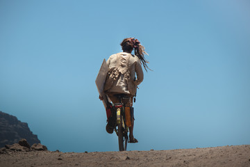 A hippie man on a bicycle in the back climbs a hill in Valle gran ray, La Gomera, Canary islands, Spain