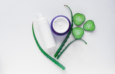 Background with natural cosmetics from aloe vera juice on white, cucumbers, jars of face cream. Aloe vera with a slice of cucumber on top on a white background.