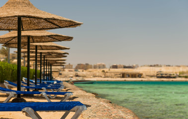 sun beds along stone coastline on summer sea beach