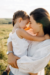 Mother hugging little daughter outdoors in a field.