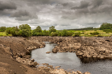 Water of Ken flowing out of a gorge on a drained or dewatered Earlstoun Dam